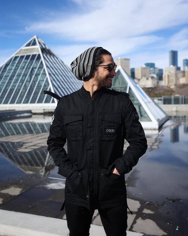 Wil Dasovich smiling in a black jacket, pants and woolen cap.